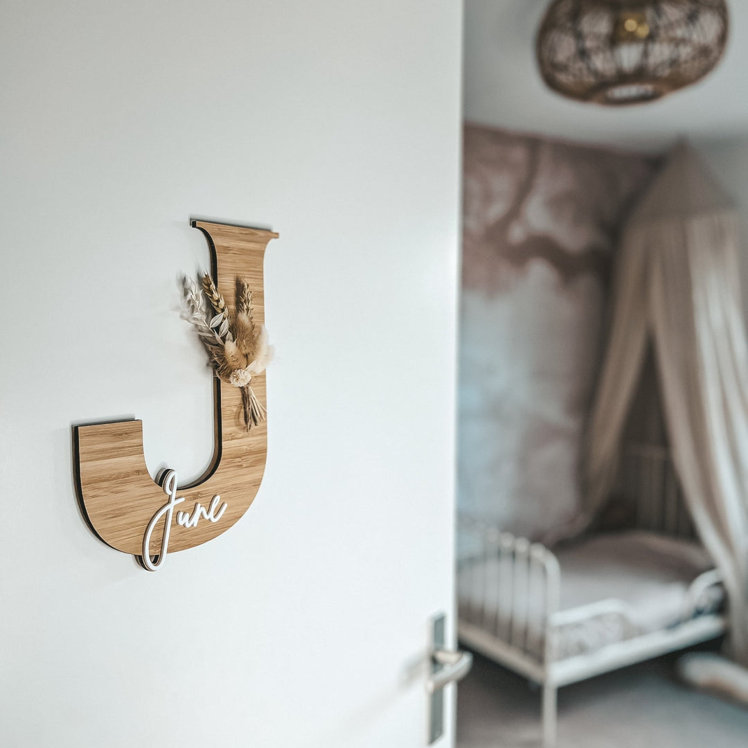 Bamboe Naambordje met Droogbloemen op een deur met op de achtergrond een kinderkamer